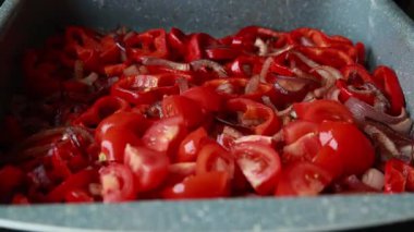  Dilimlenmiş kırmızı soğanlar ve dilimlenmiş kırmızı dolma biberler yakın bir tepside dizilmiş.