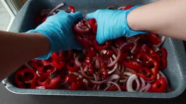  Dilimlenmiş kırmızı soğanlar ve dilimlenmiş kırmızı dolma biberler yakın bir tepside dizilmiş.