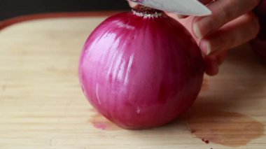  Ahşap kesim tahtasına kırmızı soğan dilimleyen kadın.