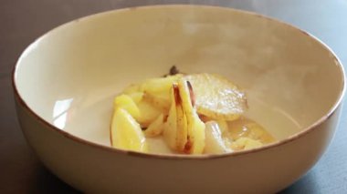 Kavrulmuş tavuk butları limon patatesleri ve arpacık soğanlarıyla dolu bir kasede.