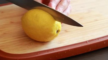  Tahta kesme tahtasındaki taze limonu kesen bir kadının elleri.