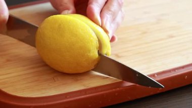  Tahta kesme tahtasındaki taze limonu kesen bir kadının elleri.