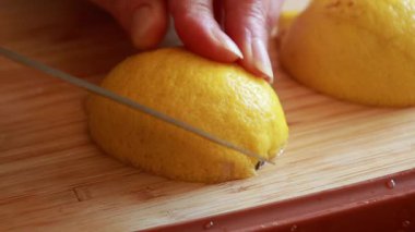  Tahta kesme tahtasındaki taze limonu kesen bir kadının elleri.