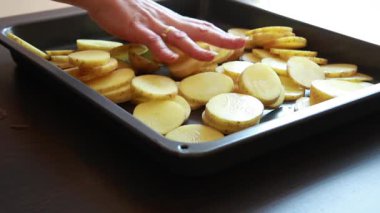 Çiğ patates dilimleri düzgün bir tepside dizilmiş.