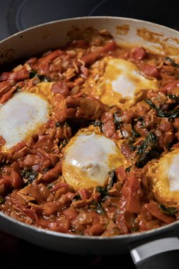 Taze pişmiş Shakshuka 'nın yakın çekimi, tavada servis edilen bol domates soslu haşlanmış yumurtalarla lezzetli bir yemek. Nefis bir kahvaltı için mükemmel..