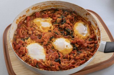 Taze pişmiş Shakshuka 'nın yakın çekimi, tavada servis edilen bol domates soslu haşlanmış yumurtalarla lezzetli bir yemek. Nefis bir kahvaltı için mükemmel..