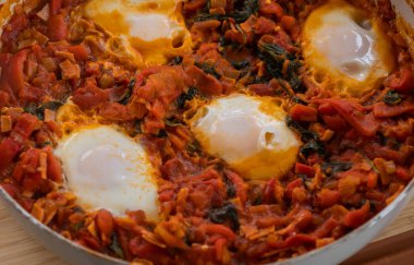 Taze pişmiş Shakshuka 'nın yakın çekimi, tavada servis edilen bol domates soslu haşlanmış yumurtalarla lezzetli bir yemek. Nefis bir kahvaltı için mükemmel..