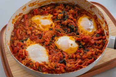 Taze pişmiş Shakshuka 'nın yakın çekimi, tavada servis edilen bol domates soslu haşlanmış yumurtalarla lezzetli bir yemek. Nefis bir kahvaltı için mükemmel..