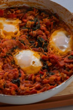 Taze pişmiş Shakshuka 'nın yakın çekimi, tavada servis edilen bol domates soslu haşlanmış yumurtalarla lezzetli bir yemek. Nefis bir kahvaltı için mükemmel..