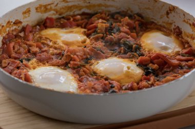 Taze pişmiş Shakshuka 'nın yakın çekimi, tavada servis edilen bol domates soslu haşlanmış yumurtalarla lezzetli bir yemek. Nefis bir kahvaltı için mükemmel..