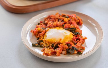 Shakshuka kavrulmuş kırmızı dolma biber, yumurta ve ıspanak yakın planda servis edilir.