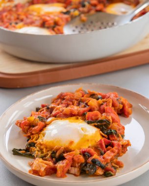 Shakshuka kavrulmuş kırmızı dolma biber, yumurta ve ıspanak yakın planda servis edilir.