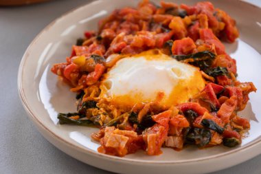 Shakshuka kavrulmuş kırmızı dolma biber, yumurta ve ıspanak yakın planda servis edilir.