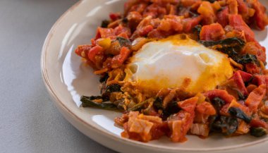 Shakshuka kavrulmuş kırmızı dolma biber, yumurta ve ıspanak yakın planda servis edilir.