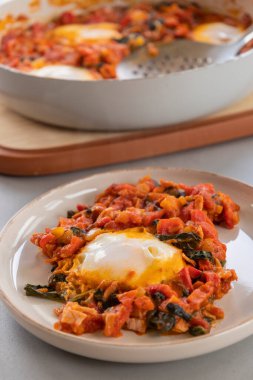 Shakshuka kavrulmuş kırmızı dolma biber, yumurta ve ıspanak yakın planda servis edilir.