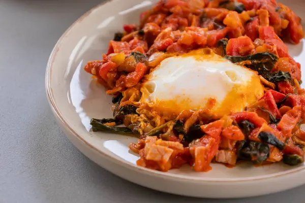 Shakshuka kavrulmuş kırmızı dolma biber, yumurta ve ıspanak yakın planda servis edilir.