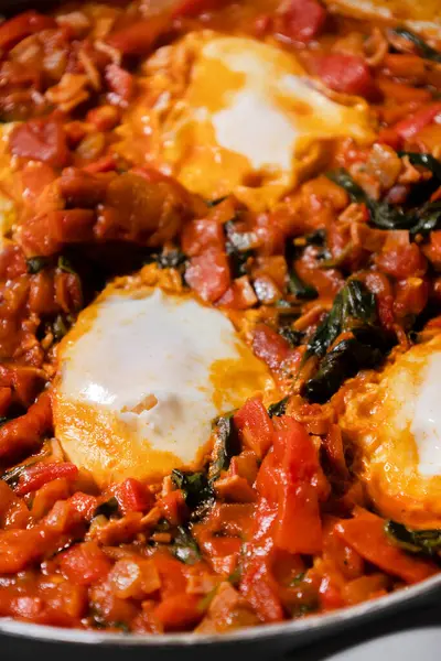 Taze pişmiş Shakshuka 'nın yakın çekimi, tavada servis edilen bol domates soslu haşlanmış yumurtalarla lezzetli bir yemek. Nefis bir kahvaltı için mükemmel..