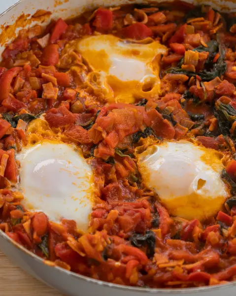 Taze pişmiş Shakshuka 'nın yakın çekimi, tavada servis edilen bol domates soslu haşlanmış yumurtalarla lezzetli bir yemek. Nefis bir kahvaltı için mükemmel..