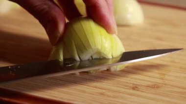  Kadın elleri ahşap kesim tahtasına sarı soğan dilimliyor.