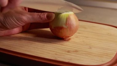  Kadın elleri ahşap kesim tahtasına sarı soğan dilimliyor.