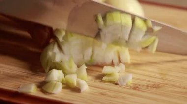  Kadın elleri ahşap kesim tahtasına sarı soğan dilimliyor.