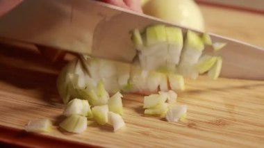  Kadın elleri ahşap kesim tahtasına sarı soğan dilimliyor.