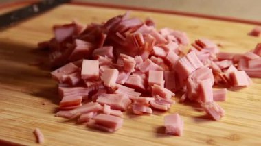Kadın elleri ahşap kesim tahtasında jambon dilimliyor.