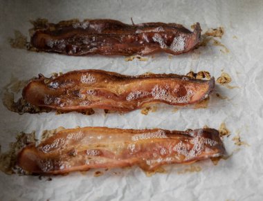 Parşömen kağıdıyla kaplanmış tepside pişmiş domuz pastırması.