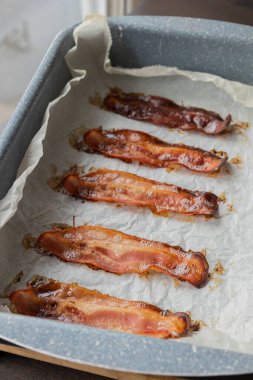 Parşömen kağıdıyla kaplanmış tepside pişmiş domuz pastırması.