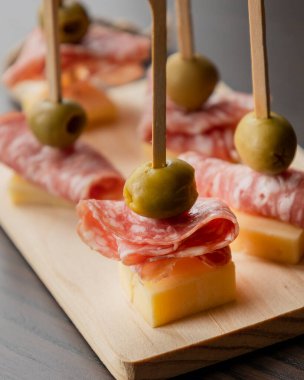  Parmesan peyniri, salam dilimleri ve yeşil zeytinle yapılan mezeler.
