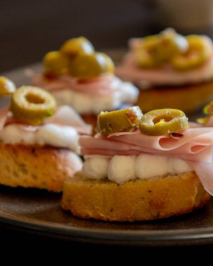 İçinde peynir, mortadella, salam ve yeşil zeytin dilimleri bulunan güzel ve narin bir parti aperatifi.