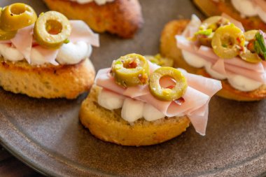 İçinde peynir, mortadella, salam ve yeşil zeytin dilimleri bulunan güzel ve narin bir parti aperatifi.