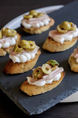 İçinde peynir, mortadella, salam ve yeşil zeytin dilimleri bulunan güzel ve narin bir parti aperatifi.