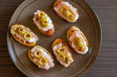 İçinde peynir, mortadella, salam ve yeşil zeytin dilimleri bulunan güzel ve narin bir parti aperatifi.