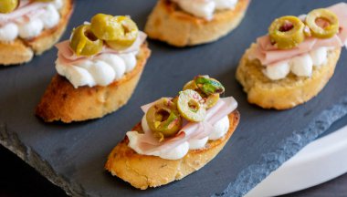 İçinde peynir, mortadella, salam ve yeşil zeytin dilimleri bulunan güzel ve narin bir parti aperatifi.
