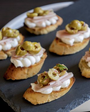 İçinde peynir, mortadella, salam ve yeşil zeytin dilimleri bulunan güzel ve narin bir parti aperatifi.