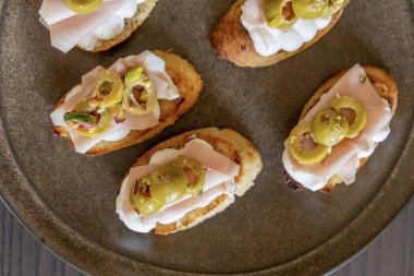 İçinde peynir, mortadella, salam ve yeşil zeytin dilimleri bulunan güzel ve narin bir parti aperatifi.