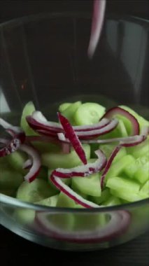 Çabuk kremalı yaz salatası, salatalıklı ve kırmızı soğanlı cam kasede dikey yakın plan.