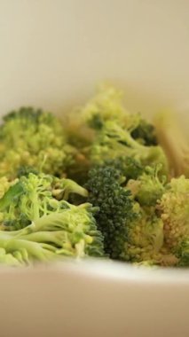 Çiğ brokoli çiçeklerinin baharatla karıştırılıp rendelenmiş parmesan peynirinin yakın çekimi.