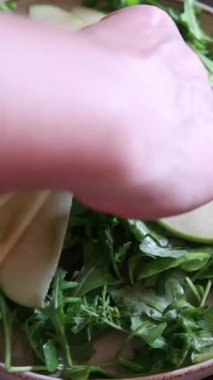 Renkli bir sonbahar salatası hazırlayan bir kadının ellerinin yakın çekimi.