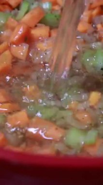 Sıcak sebze çorbası kırmızı bir tencerede kaynıyor.