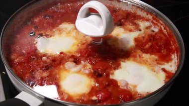 Sıcak bir tavada hazırlanan lezzetli bir Shakshuka tabağının yakın çekim görüntüleri.