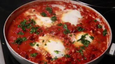 Sıcak bir tavada hazırlanan lezzetli bir Shakshuka tabağının yakın çekim görüntüleri.