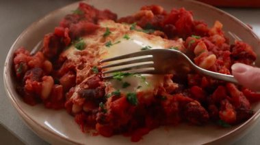 Sıcak, lezzetli bir Shakshuka 'nın yakın çekim videosu. Yumurta ve fasulye, zengin bir domates sosunda kaynıyor.