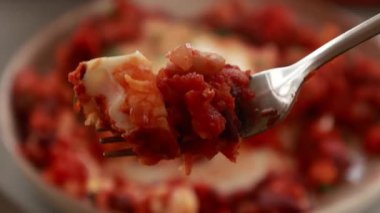 Sıcak, lezzetli bir Shakshuka 'nın yakın çekim videosu. Yumurta ve fasulye, zengin bir domates sosunda kaynıyor.