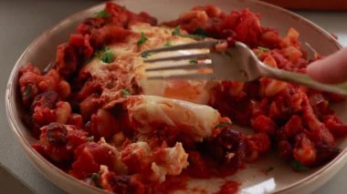 Sıcak, lezzetli bir Shakshuka 'nın yakın çekim videosu. Yumurta ve fasulye, zengin bir domates sosunda kaynıyor.