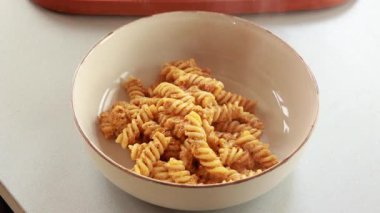 Kırmızı dolmalık biber soslu lezzetli ve kolay bir makarna tabağının yakın çekimi, rahatlatıcı bir akşam yemeği olarak sunuluyor.