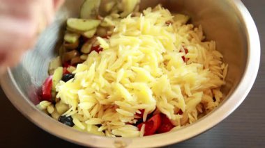Lezzetli bir orzo salatasını taze malzemelerle karıştırma videosu.