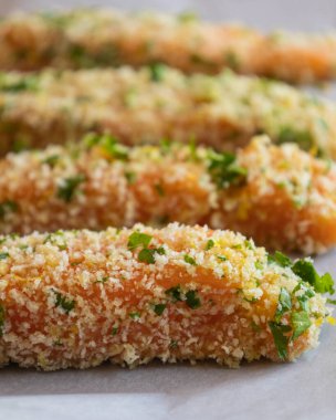 Çiğ somon fileto yakın çekim bir tepside dizilmiş, pişirilmeye hazır. Somon, ekmek kırıntılarıyla eşit kaplıdır. Doku ve tazeliği gösterir.