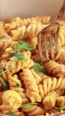 Kırmızı dolma biber sosuyla karıştırılmış makarna videosu.